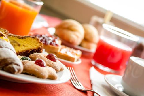 a table with a plate of breakfast foods and orange juice at Hotel della Vittoria in Ancona