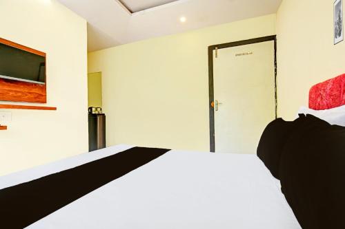 a bedroom with a bed and a tv on the wall at Hotel O Paradise Green in Indore