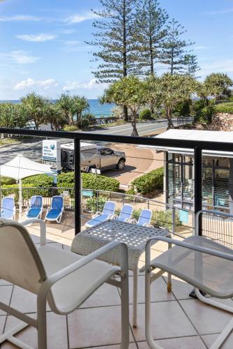 a balcony with chairs and a table and a car at The Beach Retreat Coolum in Coolum Beach