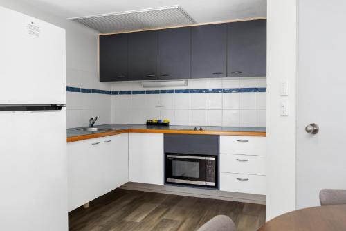 a kitchen with white cabinets and a microwave at The Beach Retreat Coolum in Coolum Beach