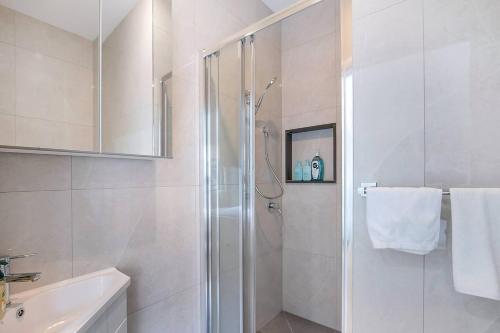une salle de bain blanche avec une douche et un lavabo dans l'établissement The Terrarena - Family Stay near Shopping & Eateries, à Brisbane