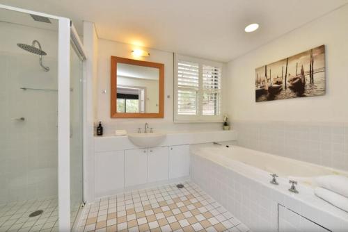Un baño blanco con bañera y lavabo. en Private 1bdr Villa Burgundy located within Cypress Lakes Resort, en Pokolbin