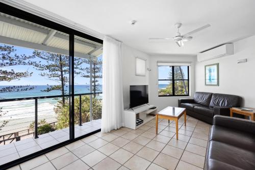 a living room with a couch and a television at The Beach Retreat Coolum in Coolum Beach