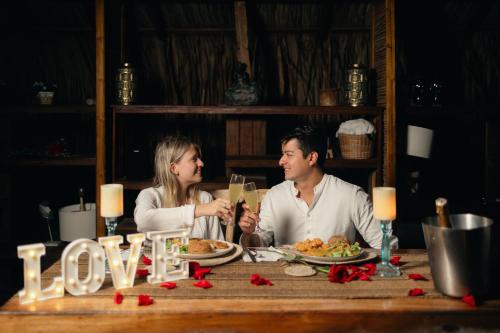 a man and woman sitting at a table with food at Hotel Isla del Sol in Isla Grande