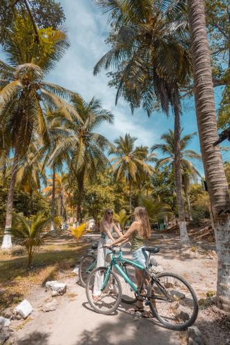 two women riding bikes on a beach with palm trees at Hotel Isla del Sol in Isla Grande
