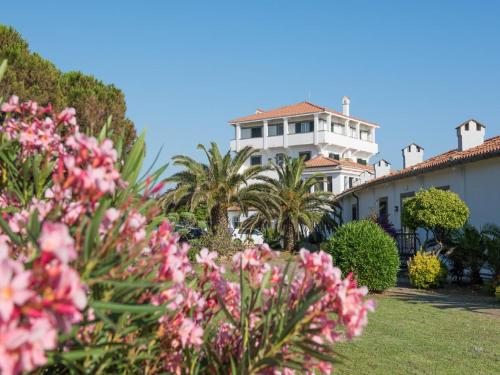 a white house with palm trees and pink flowers at Mercure Civitavecchia Sunbay Park Hotel in Civitavecchia