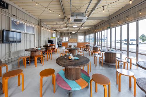 a restaurant with wooden tables and chairs and windows at 遊学の宿いさみや 