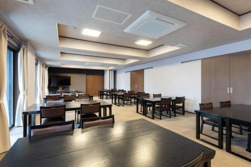 a conference room with tables and chairs and a screen at 遊学の宿いさみや 