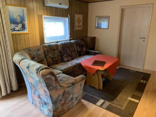 a living room with a couch and a table at Wooden holiday home with winter garden in Kleinweidelbach