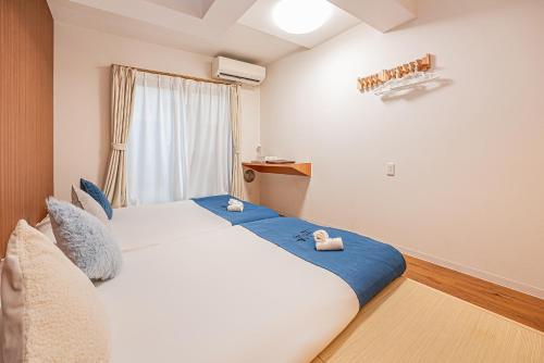 a bedroom with a large white bed with blue sheets at 桜の川10 池袋駅 7分 2-5人丨Ikebukuro 7 minutes 2-5 people in Tokyo