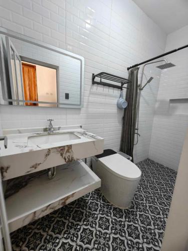 a bathroom with a sink and a toilet and a mirror at Aura Spring Resort in Los Baños