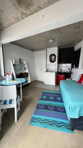 a bedroom with a bed and a table and a kitchen at My little Santorini in Guanaqueros