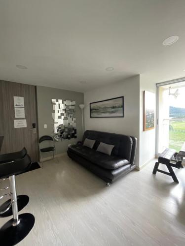 a living room with a black leather couch and chairs at Apartamento en Paipa frente al lago in Paipa
