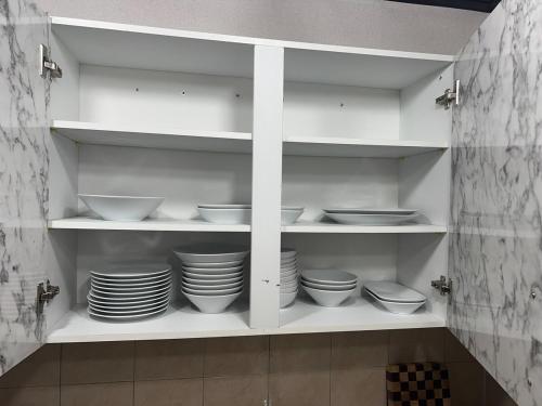 a kitchen with white shelves with bowls and plates at FLYING Stay 플라잉스테이 in Seoul