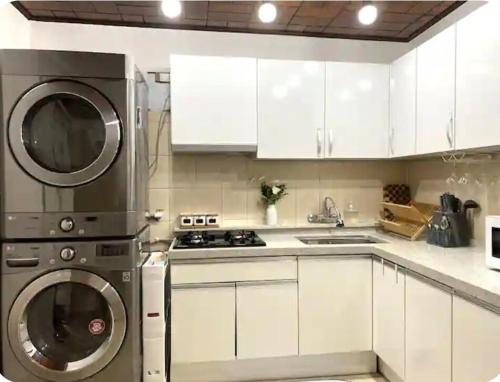 a kitchen with white cabinets and a washer and dryer at FLYING Stay 플라잉스테이 in Seoul