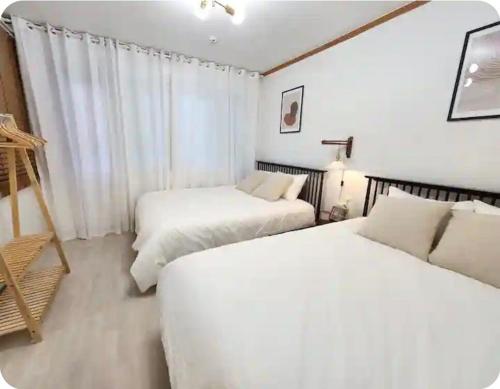 two beds in a room with white walls at FLYING Stay 플라잉스테이 in Seoul