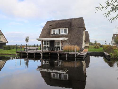 a house on a dock next to a body of water at Lakeside Villa with Terrace in Delfstrahuizen