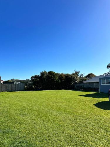 a large grass field with a blue sky in the background at Walk to the beach in Taipa