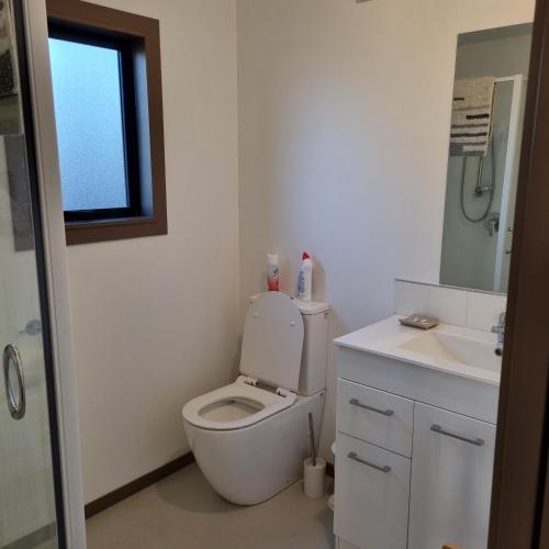 a white bathroom with a toilet and a sink at Walk to the beach in Taipa