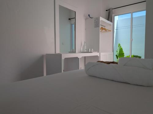a white room with a bed and a mirror at Avi Guesthouse in Thoddoo