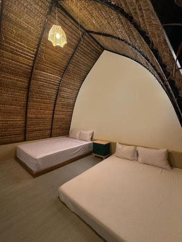 two beds in a room with a brick wall at Bukit Langit Campventure in Glagah
