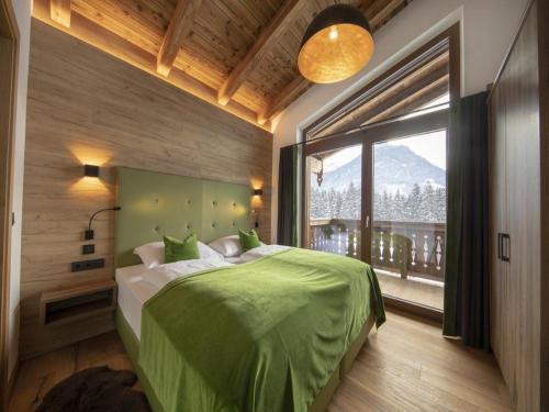 a bedroom with a green bed and a large window at Nationalpark Chalet Dreiherrenspitze in Rosenthal