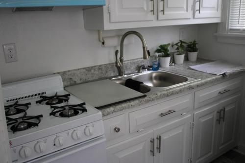 a white kitchen with a sink and a stove at Heart of Richmond Stylish stay in Richmond