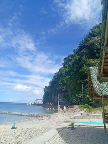 a beach with a mountain and the ocean and a building at Evashore Beach Resort in Limasawa Island