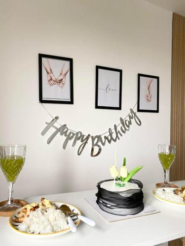 a table with plates of food and a happy birthday sign at Beans Crib Staycation at SMDC Green 2 Residences in Dasmariñas