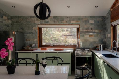 a kitchen with a counter with a window and a sink at Lodge Rio Fascinante, Pucón in Pucón