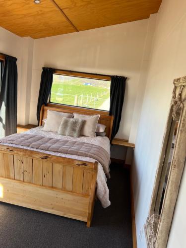 a bedroom with a wooden bed with a window at Have it all! Off the Grid Lake Opuha in Fairlie