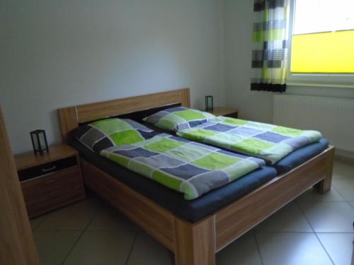 ein Bett mit einer blauen und grünen Bettdecke in einem Schlafzimmer in der Unterkunft Ferienwohnung Hilbers in Horumersiel