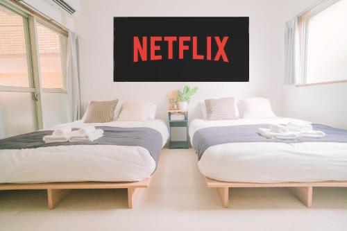 two beds in a room with a netflix sign on the wall at リトリートコート薬院 in Fukuoka