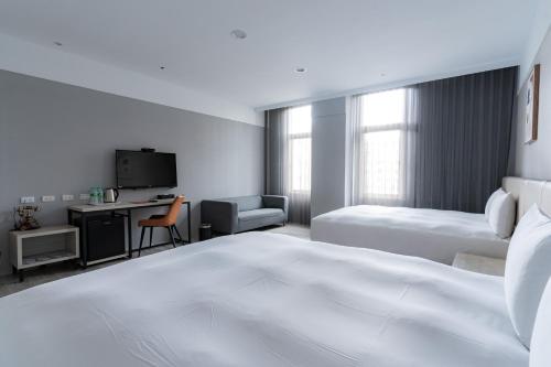 a white hotel room with two beds and a desk at Fengjia JinRui Hotel in Taichung