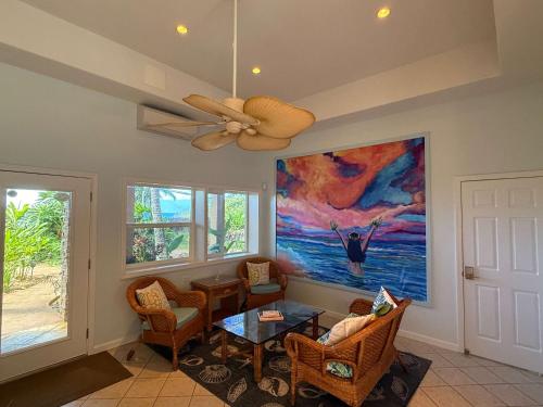 a living room with a ceiling fan and a painting at Beachfront B&B w Free Breakfast, AC & Sunset View in Lahaina