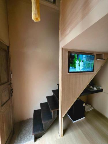 a living room with a staircase with a tv on the wall at Blu Cabin Ari Stylish Gay Poshtel in Bangkok