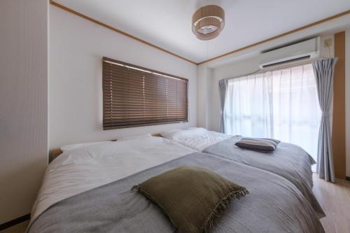 a bedroom with a large bed with a window at Cozy Nest Sangenjaya 1 Stop to Shibuya ーWalk to Sangenjaya and Ikejiri in Tokyo