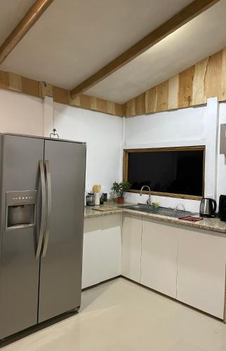 a kitchen with a stainless steel refrigerator and white cabinets at Cabaña 23 - private cabin in Montaña Azul