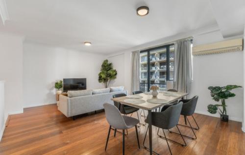 a living room with a table and chairs and a couch at East Perth modern 2 Bedroom with Pool & parking in Perth
