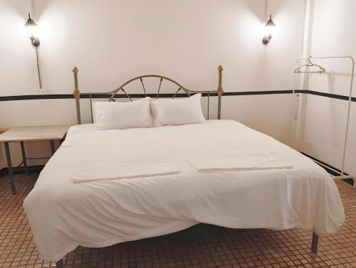 un lit avec des draps blancs et des oreillers dans une chambre dans l'établissement Toss Inn Hat Yai OldTown - ทอส อินน์ หาดใหญ่ ตลาดกิมหยง, à Hat Yai
