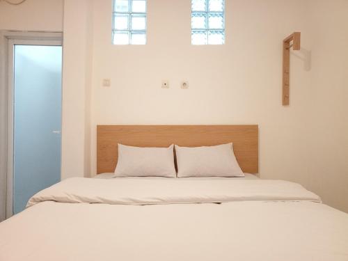 a bedroom with a bed with white sheets and two windows at JS Sentul City Syariah in Cibitung