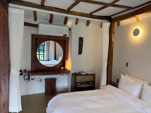 a bedroom with a white bed and a mirror at Imjingotaek Hanok Stay Jeju Traditional House LP Cozy House, Wagon stay at Imjingotaek in Jeju