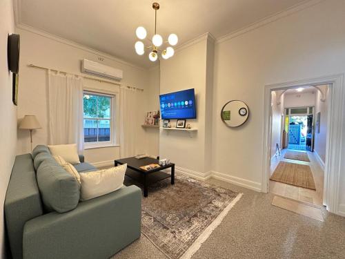 a living room with a couch and a tv at Charming 2BR Cottage in City Fringe Norwood in Rose Park