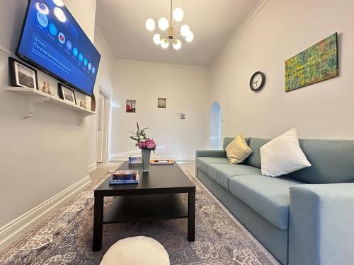 a living room with a blue couch and a table at Charming 2BR Cottage in City Fringe Norwood in Rose Park