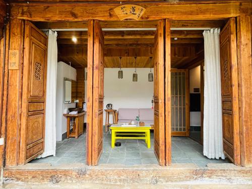 a living room with a yellow table in a room at Dali Xizhou Jiakedi 大理喜洲甲科第古宅文化民宿 in Dali
