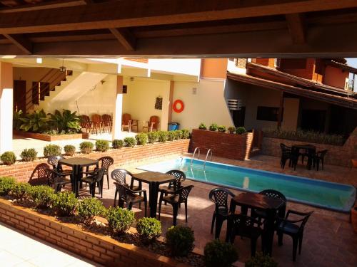 a patio with tables and chairs next to a swimming pool at Pousada Paraiso in Bonito