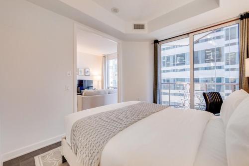a bedroom with a white bed and a large window at 2BR Yorkville Condo - Self Check In & Free Parking in Toronto