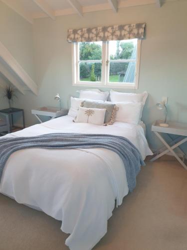 a bedroom with a large white bed with a window at Brenton Lodge in Whangamata