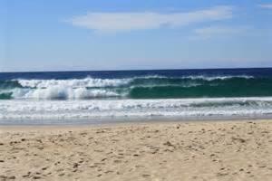 a person standing on a beach with the ocean at Mollymook Fantastic Holiday House in Mollymook