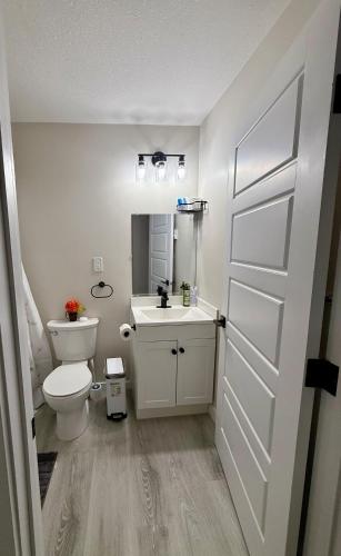 a white bathroom with a toilet and a sink at Newly Built Cozy Cove Suite in Regina